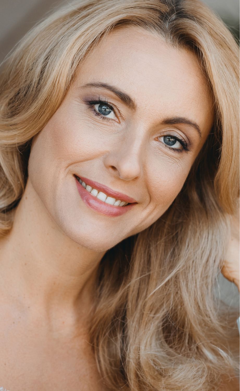 Smiling Eatontown med spa model with long, wavy blonde hair.